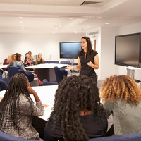 Female teacher addressing university students in a classroom